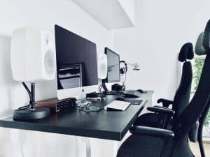 Przestrzeń do pracy w domu z dwoma monitorami i sprzętem audio.