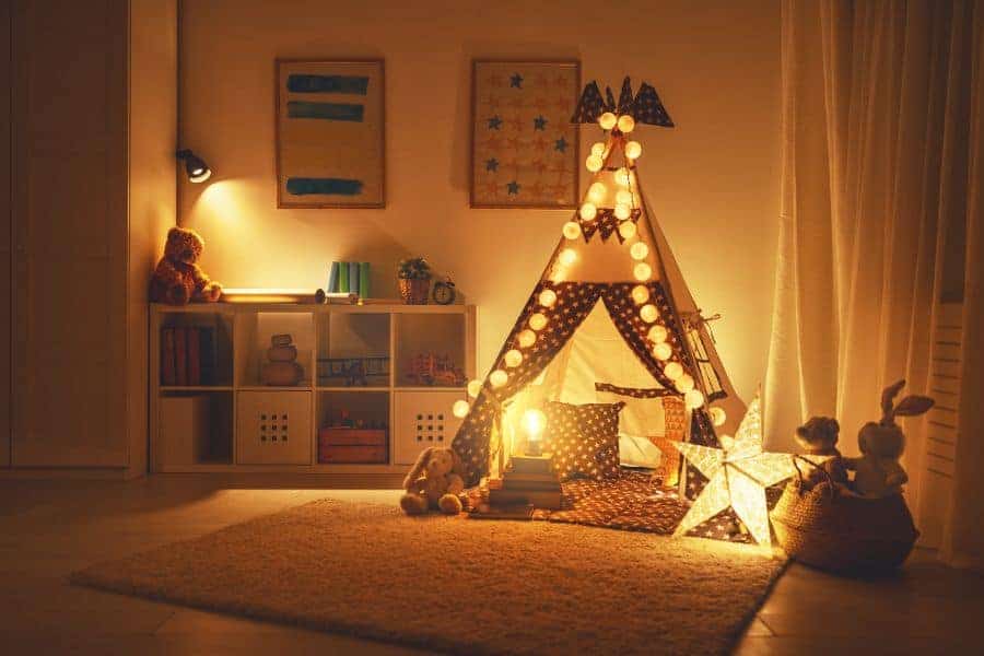 Przytulny pokój zabaw z lampkami, tipi i zabawkami dla dzieci.