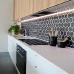 Kuchnia z czarnym hexagonalnym backsplash i drewnianymi szafkami.