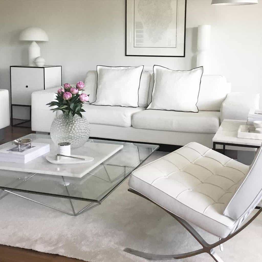 Biały minimalistyczny salon z sofą, fotelami i dekoracjami.