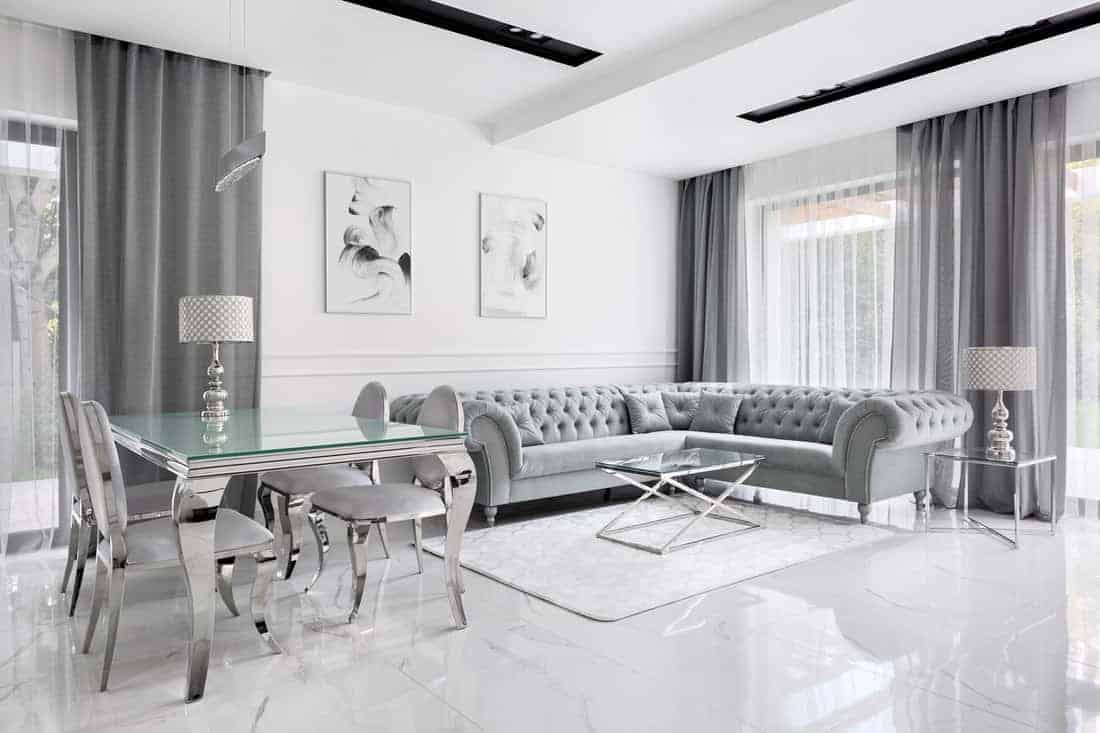 Nowoczesny biało-srebrny salon z wygodną sofą i eleganckim stołem.