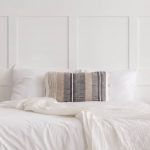 Przytulna minimalistyczna sypialnia w stylu Boho z białą pościelą i dekoracyjnym poduszką.
