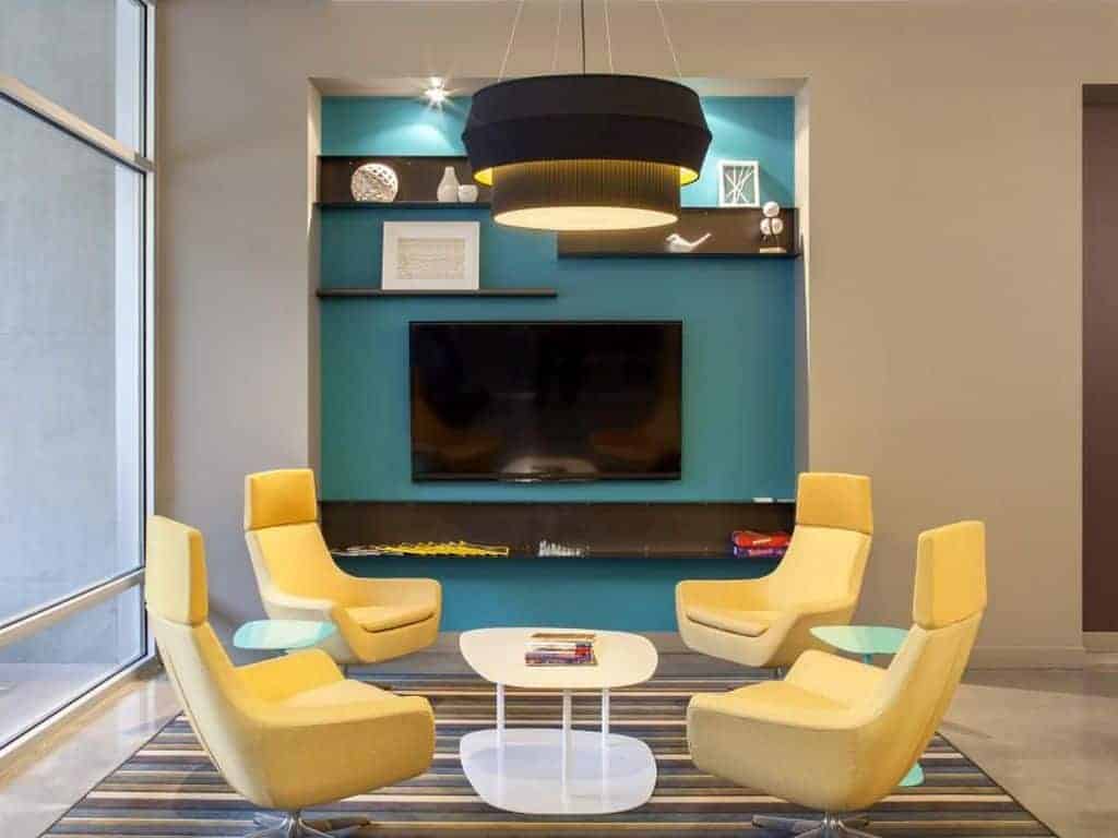 Salon z turkusową ścianą, żółtymi fotelami i nowoczesnym designem.