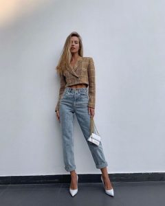 Stylowa kobieta w przyciętej marynarce i jeansach na wiosnę.