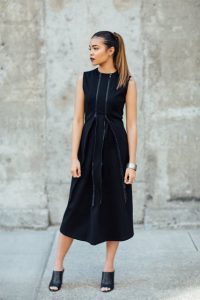 Elegancka kobieta w czarnej sukience na suwak z przodu na ulicy.