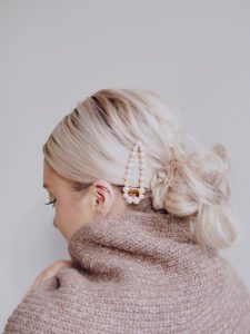 Mama z perłowymi spinkami w eleganckim upięciu włosów.