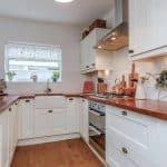 Przytulna kuchnia z białymi szafkami i ceramicznymi płytkami backsplash.