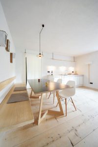 Nowoczesna, minimalistyczna jadalnia z drewnianym stołem i białymi krzesłami.