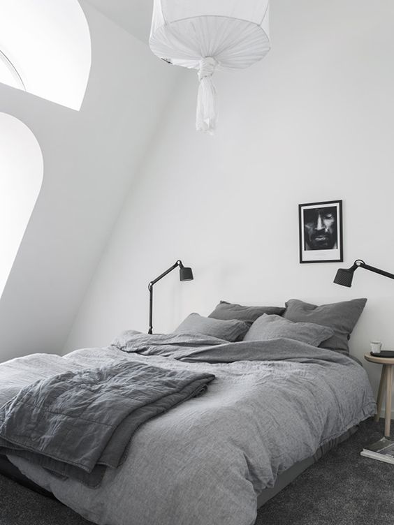 Minimalistyczna sypialnia w stylu skandynawskim z szarymi pościelami.