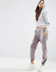 Kobieta w szarym crop topie i aksamitnych spodniach jogger.