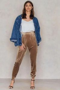 Modelka w aksamitnych spodniach jogger i jeansowej kurtce.