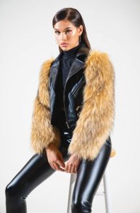 Kobieta w eleganckiej stylizacji z kurtką o puszystych rękawach.