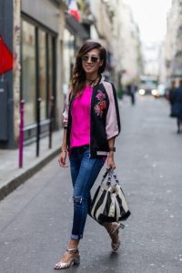 Kobieta w satynowej kurtce bomber na ulicy, modny look, stylizacja na co dzień.