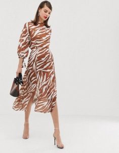Elegancka kobieta w zwiewnej sukience zebra na białym tle.